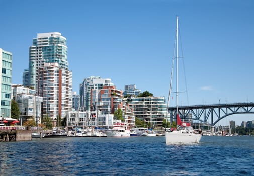 Condominium buildings and a marina are facing False Creek, a short inlet in the heart of Vancouver, British Columbia, Canada. False Creek separates downtown from the rest of the city while being crossed by Granville bridge.
