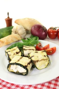 stuffed zucchini rolls and tomatoes on a white plate