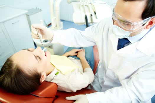 Smiling woman sitting in dentist’s chair while doctor examining her teeth