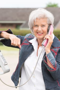 Smiling elderly woman at a telephone booth