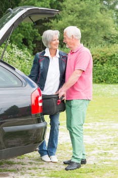 Senior couple loading a car with a suitcase