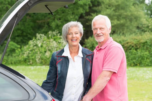 Senior couple loading a car with a suitcase