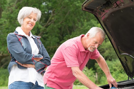 Senior couple at a black car with an open hood