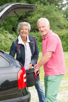 Senior couple loading a car with a suitcase