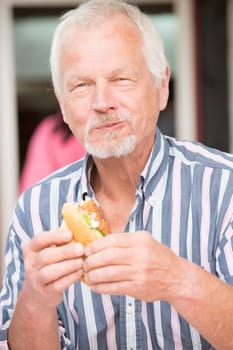 Smiling senior eats a fish sandwich