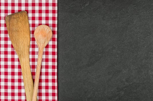 Wooden spoon on a slate plate with a red checkered tablecloth