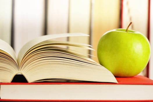 Composition with green apple and books on the table