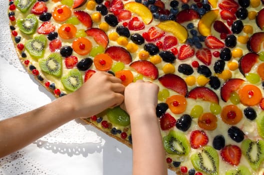 the hands of children who steal the fruits from the cake