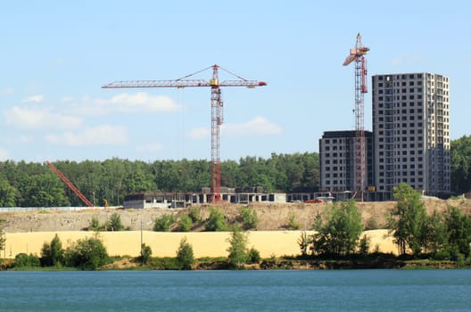 Building crane and building under construction against blue sky