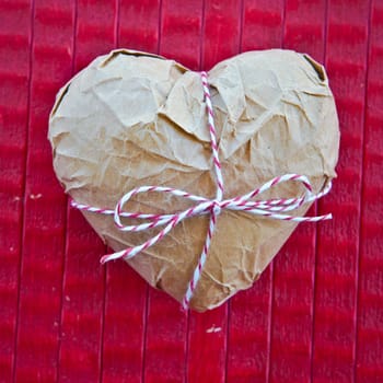 Heart in parcel paper on red background