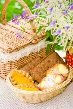 Buns in a wicker basket and a bouquet of field flowers close-up