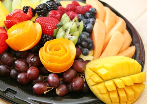 Variety of fruit on a plate includes strawberry, grapes, blueberries, blackberies, kiwi, melon, rasberry, mango,tropical, juicy, fresh, healthy