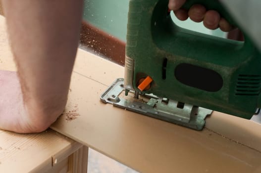 close up image of an electric jigsaw sheet on a wooden plank