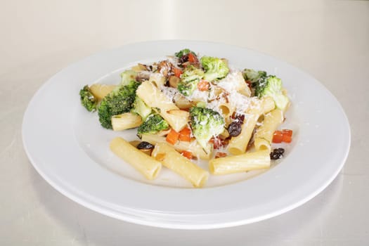 Rigatoni with vegetables served on a white plate.
