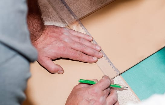 cropped hand of a carpenter taking a measurement of panels