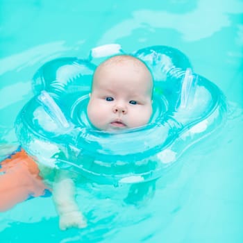 Baby swimming with neck swim ring in pool