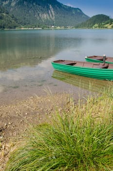 Lake in the Tyrolean mountains in the Tannheimer Tal with green wooden boat