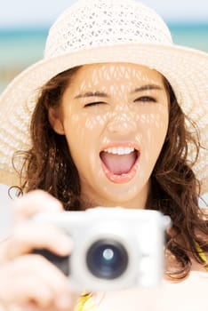 Attractive cheerful summer woman talking pictures with digital camera.