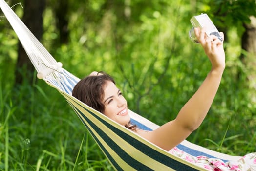 young woman lying in a hammock in the garden doing snapshot.