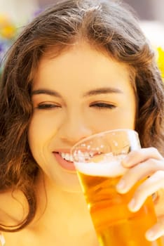 attractive young woman drinking beer on sidewalk cafe.
