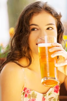 Attractive young woman drinking beer on sidewalk cafe.