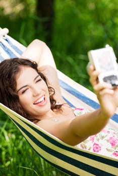 young woman lying in a hammock in the garden doing snapshot.