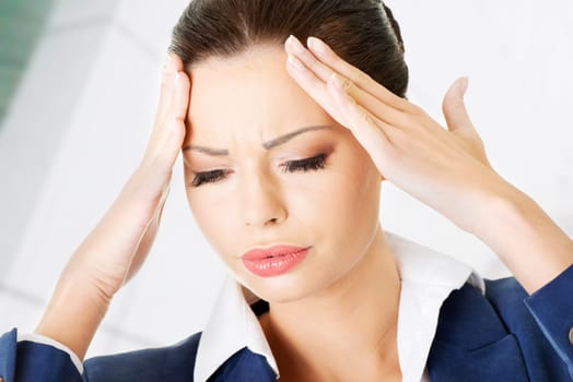 a businesswoman with a headache holding head