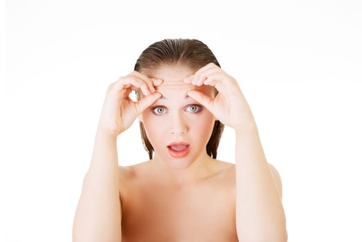 woman checking her wrinkles on her forehead - isolated on white