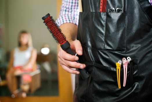 man working as hairdresser standing with brush in hands and client reflected on mirror