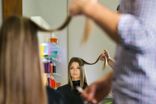 woman looking at mirron and cutting hair in hairdresser shop