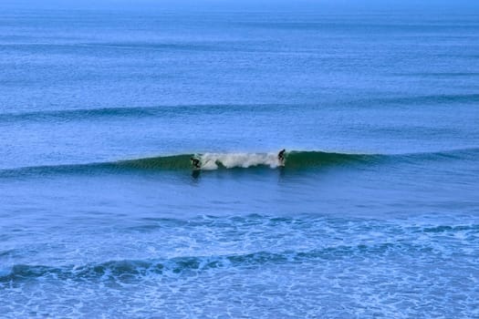 beautiful clean atlantic ocean with two surfers catching the waves on Irelands coast