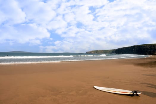 sandy golden beach with lone surfboard lying on the sand in ballybunion county Kerry Ireland