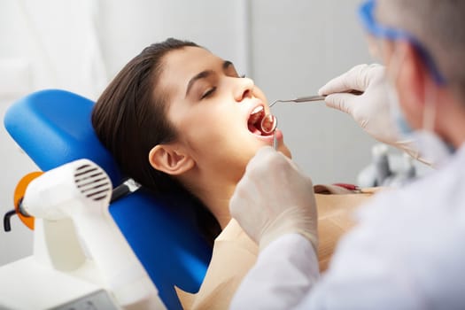 Close-up of girl with open mouth during oral checkup at the dentist’s