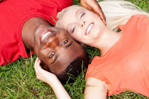 Young in love multicultural couple on a meadow in summer leisure fun