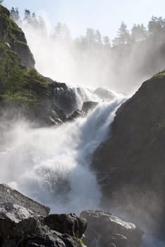 a huge and wild waterfall with trees surrounding it