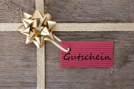 a red tag haning on a golden bow with the german word gutschein on it which means voucher