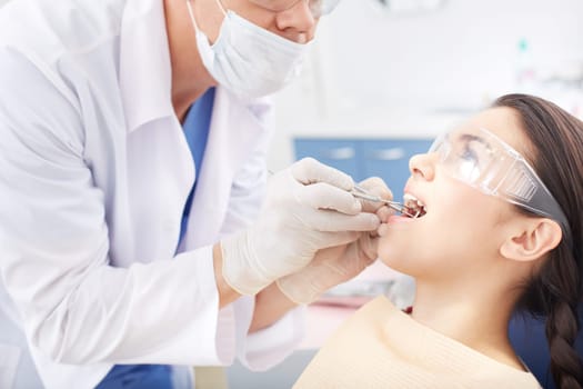 Young girl with open mouth during oral checkup at the dentist’s