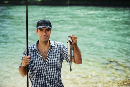 mid adult fisherman on holidays on river, relaxing and fishing trout. Copy space
