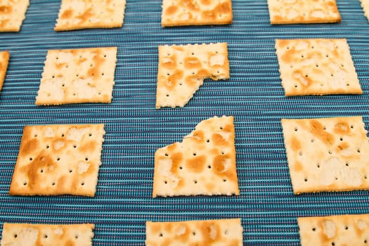 Lots of salted crackers and ones bitten, background.
