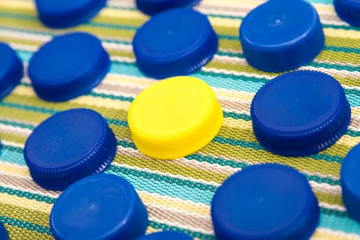 Many blue plastic lids and in the middle one yellow lid.