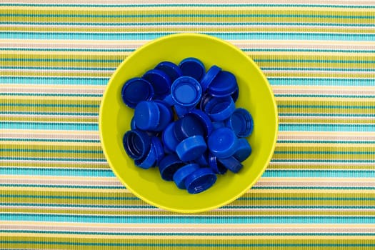 Many plastic blue lids on a green bowl..