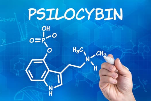 Hand with pen draws chemical structural formula of psilocybin