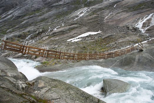 a small plank bridge over a torrential river