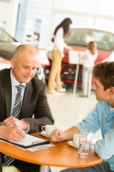 Buying family car salesman filling purchase agreement