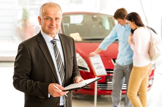 Portrait of middle aged salesman in car retail store