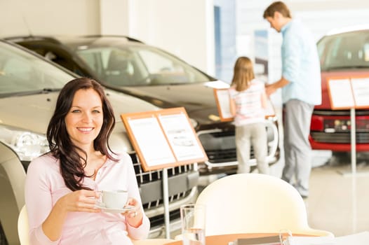 Female customer drinking coffee in car retail store