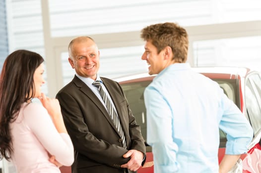 Customers talking with car agent in showroom