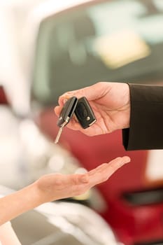 Closeup of woman's hand receiving car keys from agent