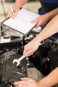 Closeup of hand of car mechanic pointing with wrench