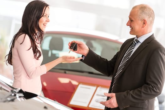 Salesman handing car keys to smiling woman